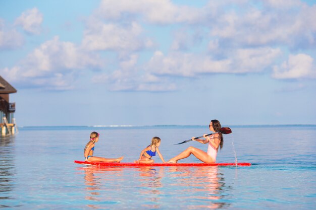 Madre e bambine sulla tavola da surf durante le vacanze estive