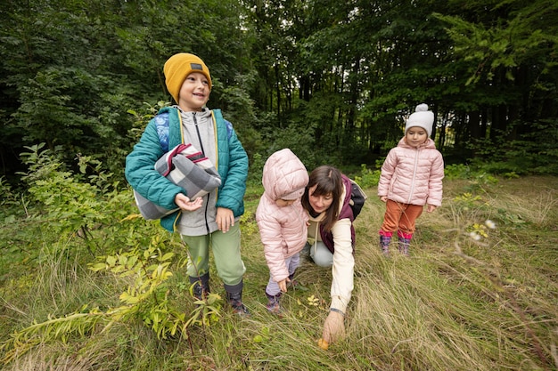 Madre e bambini alla ricerca di funghi nella foresta selvaggia