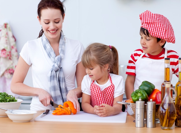 Madre e bambini che tagliano le verdure in cucina
