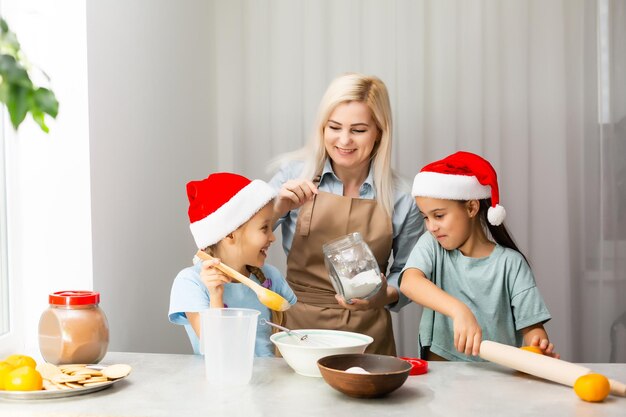 madre e bambini felici e divertenti preparano i biscotti di Natale