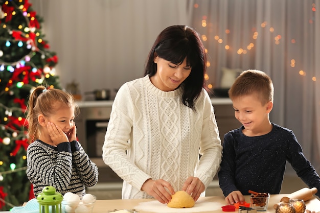 Madre e bambini piccoli che preparano i biscotti di Natale in cucina