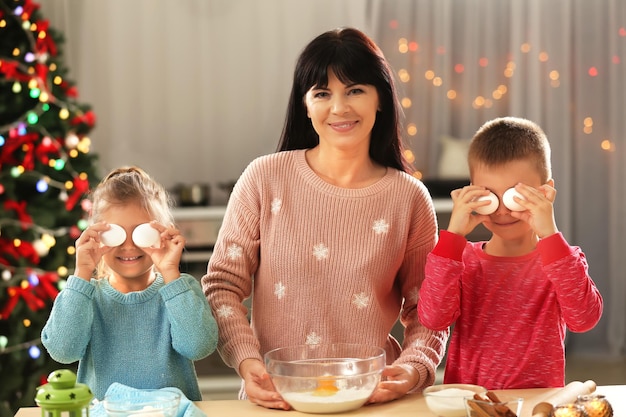 Madre e bambini piccoli che preparano i biscotti di Natale in cucina