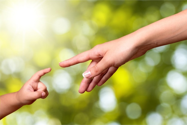 Madre e bambino che raggiungono le mani e fiori primaverili in fiore sullo sfondo