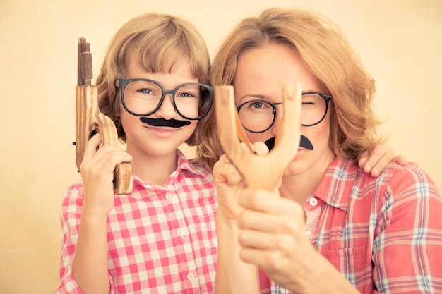 Madre e bambino con baffi finti Famiglia felice che gioca in casa