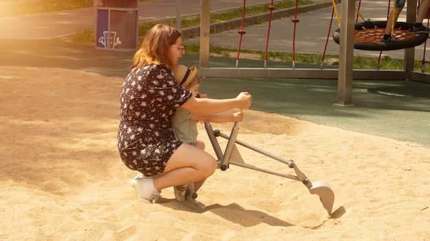 Madre e bambino giocano all'escavatore nel parco giochi