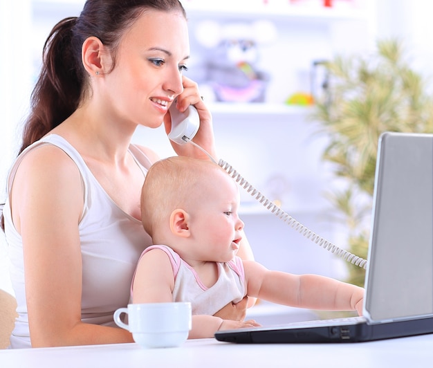 Madre e bambino in ufficio a casa con computer portatile e telefono