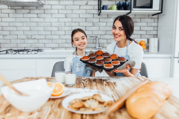 Madre e bambino piccolo in cucina a casa bellissimi e felici grembiuli