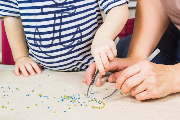 Madre e bambino realizzano un motivo di perline sul tessuto Workplace per la creatività artigianale