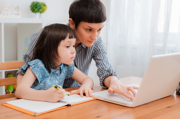 Madre e bambino studente di scuola a casa su un computer portatile a casa di apprendimento. e-home school nel periodo della pandemia e del coronavirus. Formazione per l'assistenza ai genitori.