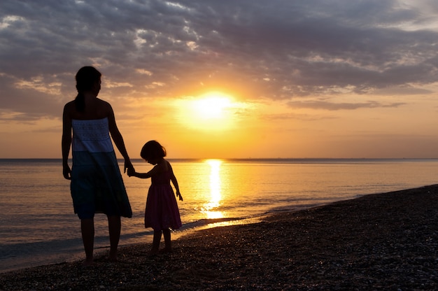 Madre e bambino sulla spiaggia al tramonto