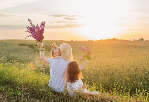 Madre e due figlie piccole per una passeggiata in campo al tramonto