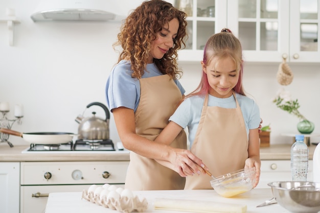 Madre e figlia adolescente che preparano insieme la pasta per la pasticceria in cucina