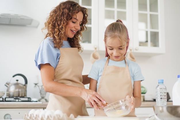 Madre e figlia adolescente che preparano insieme la pasta per la pasticceria in cucina