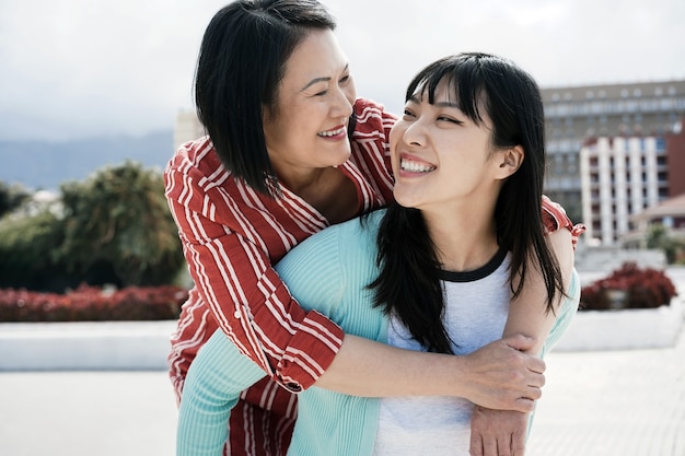 Madre e figlia asiatiche che si divertono all'aperto in città - Focus principale sul viso della ragazza