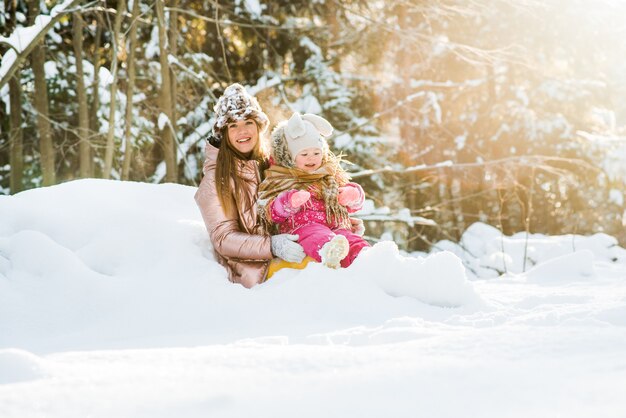 Madre e figlia avvolta in una sciarpa in una foresta invernale innevata. viaggi e ricreazione