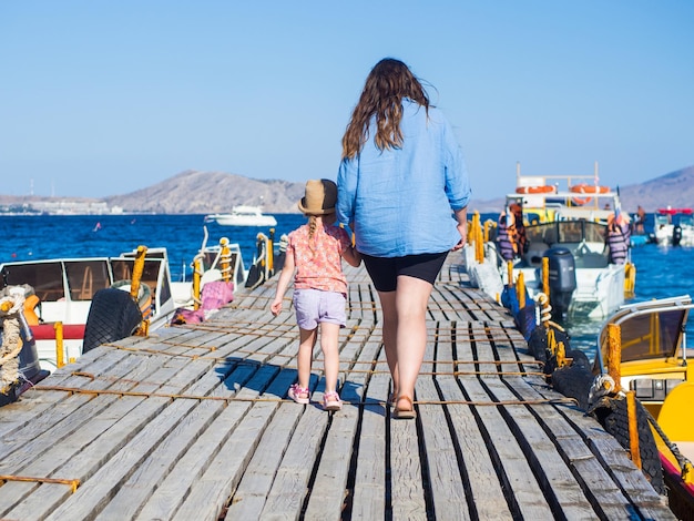 madre e figlia camminano lungo il molo verso la barca
