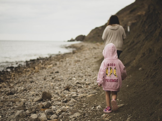 madre e figlia camminano lungo la riva della spiaggia i turisti della città camminano sul sentiero di montagna lungo la costa della spiaggia