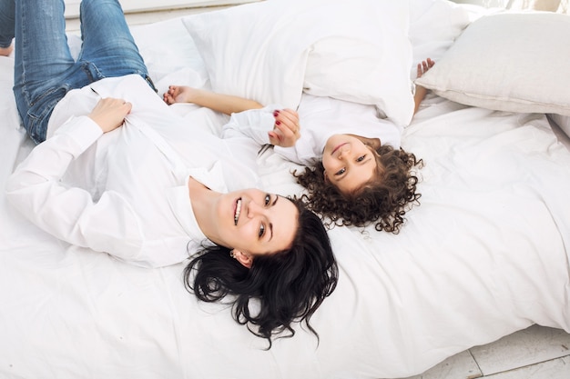 Madre e figlia carine belle e felici sul letto in camera da letto a casa insieme