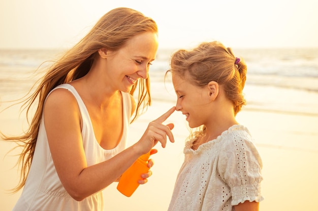 Madre e figlia che applicano la protezione solare sul corpo spf