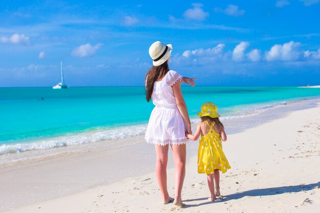 Madre e figlia che camminano lungo una spiaggia tropicale