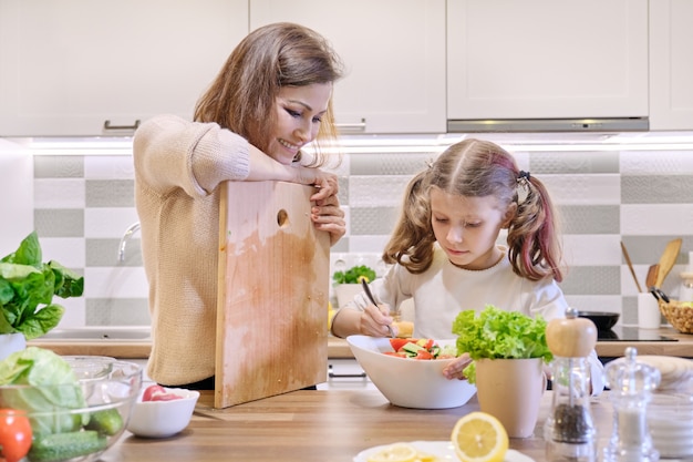 Madre e figlia che cucinano insieme nell'insalata di verdure della cucina