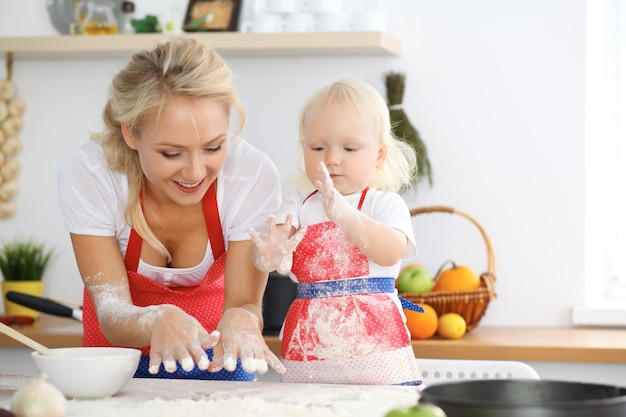 Madre e figlia che cucinano torta o biscotti per la festa della mamma. Concetto di famiglia felice in cucina.