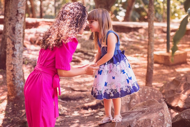 Madre e figlia che danno un bacio eschimese. Festa della mamma. Madre afro e figlia bianca