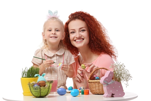 Madre e figlia che decorano le uova di Pasqua isolate su bianco
