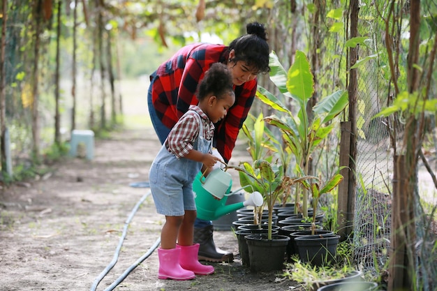 Madre e figlia che fanno attività all'aperto in giardino famiglia diversificata felice weekend di maternità insieme al concetto di festa della mamma del bambino