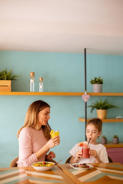 Madre e figlia che fanno colazione con succhi di frutta freschi nella caffetteria