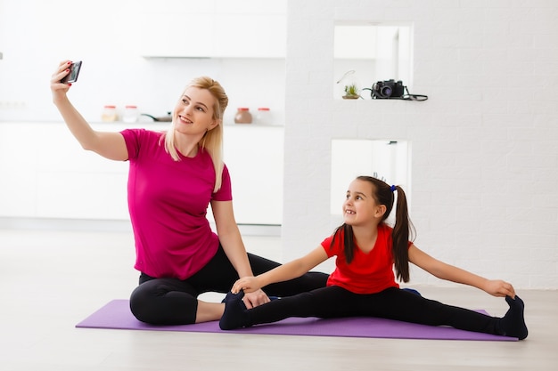 Madre e figlia che fanno esercizi di yoga sul tappetino a casa.