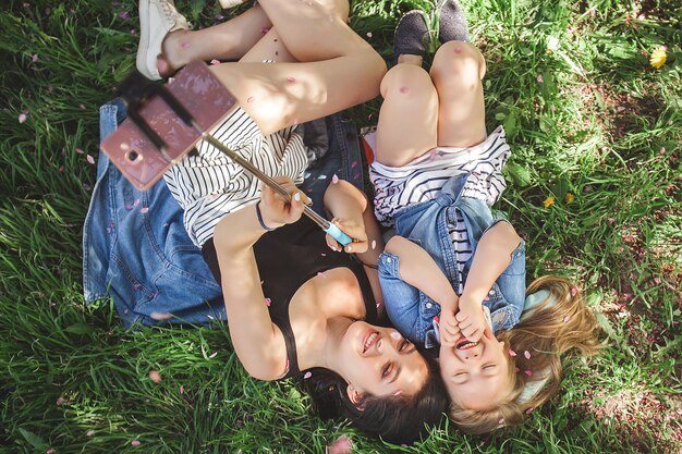 Madre e figlia che fanno selfie al parco. Ragazze che sparano sul telefono cellulare