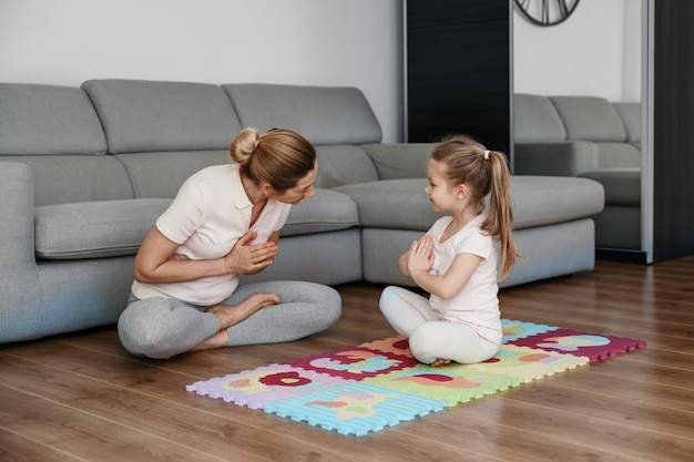 Madre e figlia che fanno yoga insieme a casa