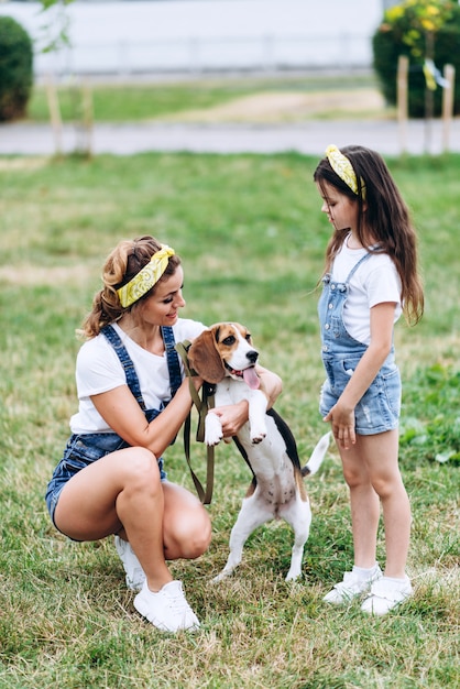 Madre e figlia che giocano con il cane all'aperto.