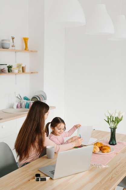 Madre e figlia che giocano mentre fanno colazione in cucina.