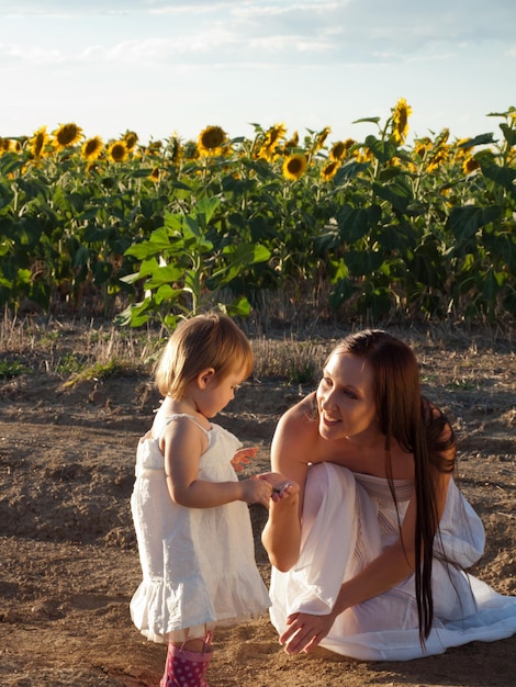 Madre e figlia che giocano nel campo di girasoli.