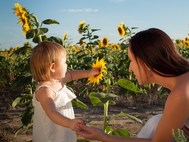 Madre e figlia che giocano nel campo di girasoli.