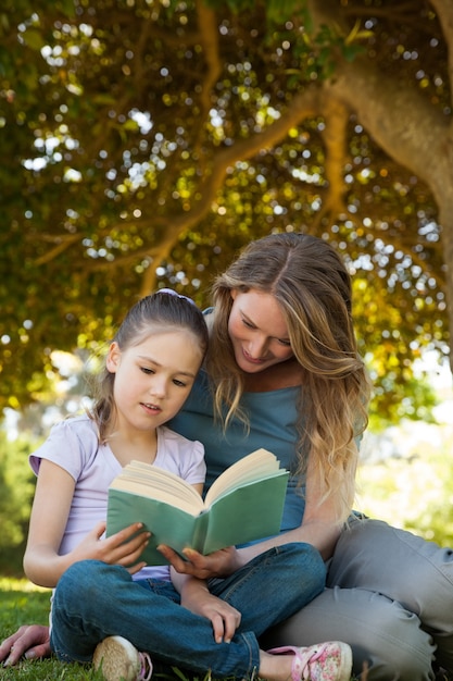 Madre e figlia che leggono un libro al parco