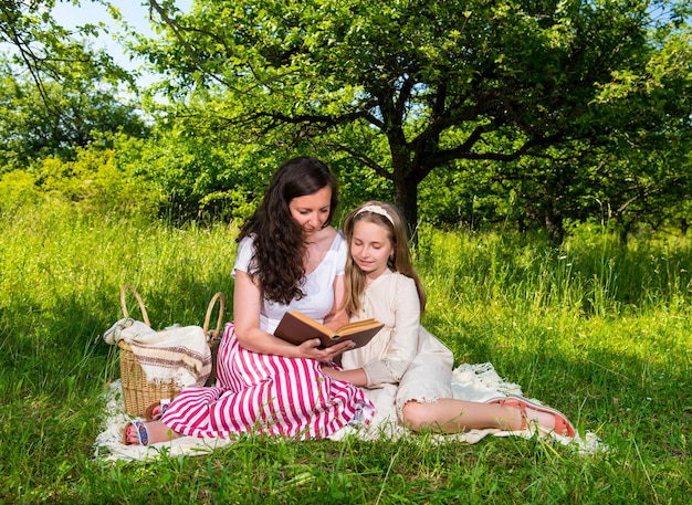 Madre e figlia che leggono un libro nel parco. Tempo per la famiglia