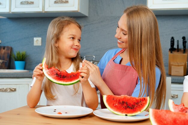 Madre e figlia che mangiano anguria a casa