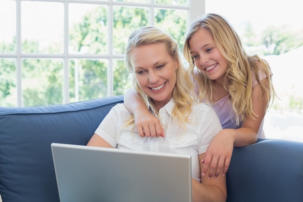 Madre e figlia che per mezzo del computer portatile sul sofà