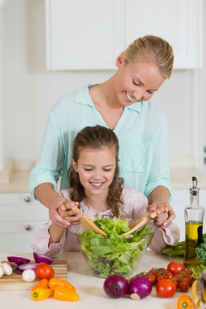 Madre e figlia che preparano insalata in cucina a casa
