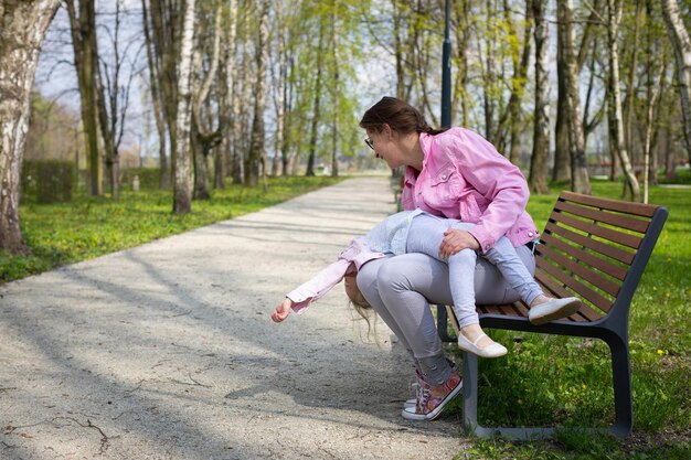 Madre e figlia che scherzano seduti su una panchina in un parco della città