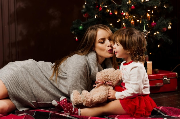 Madre e figlia che si preparano per la celebrazione del Natale. Divertirsi con la famiglia vicino all'albero di Capodanno. Donna incinta con figlia.