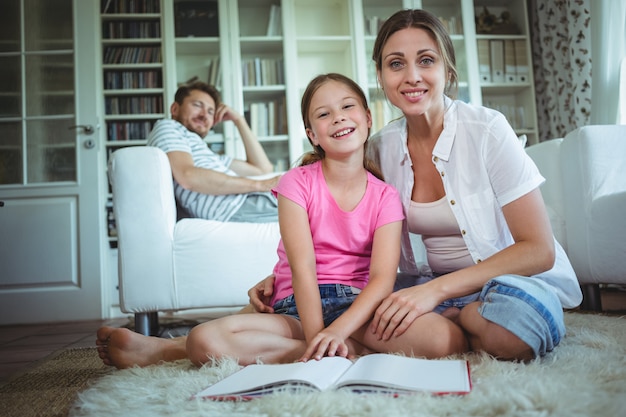 Madre e figlia che si siedono sul pavimento e che esaminano l'album di foto