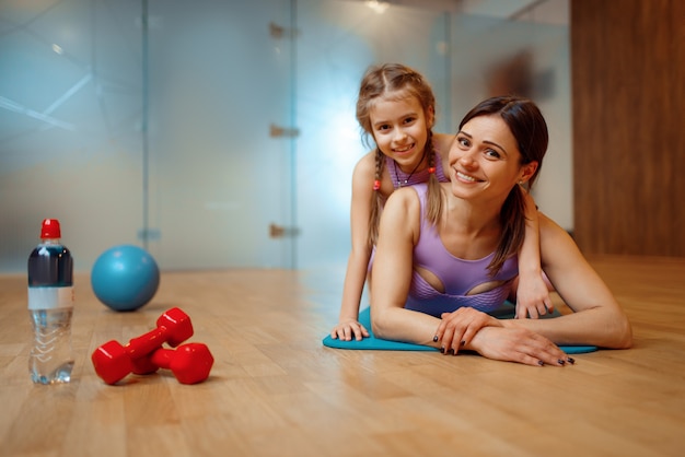 Madre e figlia che si trovano insieme sulla stuoia in palestra