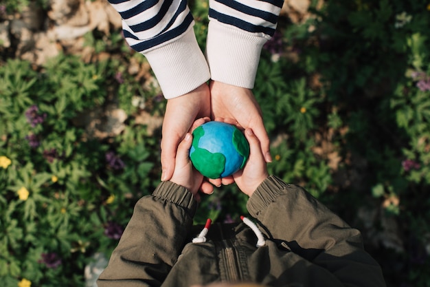Madre e figlia che tengono la terra su sfondo verde primavera.