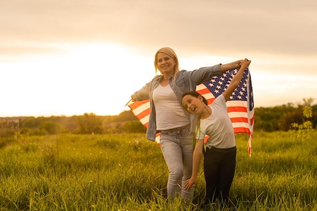 Madre e figlia con bandiera americana in un bellissimo campo.