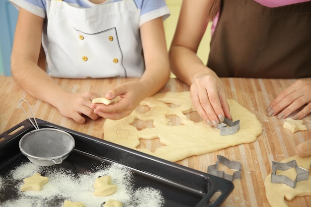 Madre e figlia con pasta biscotto al tavolo al chiuso