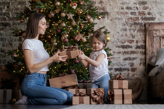 Madre e figlia davanti all'albero di Natale, regali di apertura